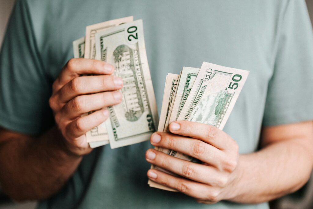 pexels-photo-4386431-4386431 Close-up of a person counting US dollar bills indoors. Financial concept.