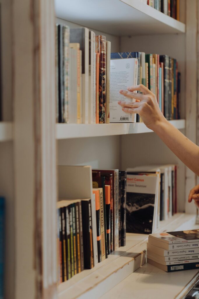 pexels-photo-4865741-4865741 A person organizing books on a library bookshelf, focusing on literature and education.